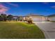 Dusk view of a charming single-story home with a screened-in lanai and well-lit exterior at 592 Netherwood Pl, The Villages, FL 32163