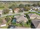 Aerial view of a neighborhood featuring a home with a screened-in pool, surrounded by mature trees and landscaping at 610 Espana St, Lady Lake, FL 32159