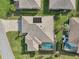 Aerial view of a home with a screened pool, solar panels, well-maintained landscaping, and a paved driveway at 610 Espana St, The Villages, FL 32159