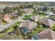 Scenic aerial of a neighborhood, highlighting a home with a pool, lush landscaping, and proximity to a lake at 610 Espana St, The Villages, FL 32159