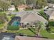 Aerial view of a home with a screened-in pool, lush landscaping, and well-maintained outdoor space at 610 Espana St, The Villages, FL 32159