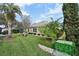 Lush green backyard featuring well-maintained landscaping, shrubbery and a peek at a screened pool enclosure at 610 Espana St, The Villages, FL 32159