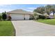 Home featuring a three car garage, well-maintained lawn, and well kept landscaping at 610 Espana St, The Villages, FL 32159