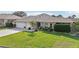 Inviting front of home with manicured lawn, colorful flowerbeds, and convenient two-car garage at 610 Espana St, The Villages, FL 32159