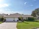 Inviting single-story home featuring lush green lawn, well-kept landscaping, and a spacious two-car garage at 610 Espana St, The Villages, FL 32159