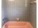 Retro bathroom with gray tile, pink bathtub, and vintage fixtures, showcasing a unique charm at 616 N Hartley Cir, Deltona, FL 32725