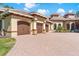 View of home with multi-car garage, brick driveway, and manicured lawn at 6801 Silver Charm Ct, Leesburg, FL 34748