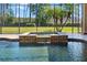 Close up of a stunning pool with a tranquil waterfall, surrounded by a screened enclosure and lush greenery at 6801 Silver Charm Ct, Leesburg, FL 34748