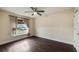 A neutral bedroom with a ceiling fan and large window overlooking the front yard at 902 Chestnut Dr, Fruitland Park, FL 34731