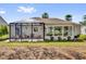 Manicured lawn leads to a screened lanai and sunroom addition with golf course view at 1029 Soledad Way, The Villages, FL 32159