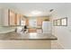 Bright kitchen with white appliances, wood cabinets, breakfast bar, and easy-to-clean tiled floors at 1100 Blythe Way, The Villages, FL 32162