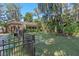 Backyard view featuring trees and landscaping with wrought iron fence at 11215 Dead River Rd, Tavares, FL 32778