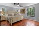 Comfortable bedroom with wood floors, windows, a king bed, and decorative painting at 11215 Dead River Rd, Tavares, FL 32778