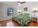 Bright bedroom featuring a tropical-themed bed set, wood flooring, and natural light from the outdoor view at 11215 Dead River Rd, Tavares, FL 32778