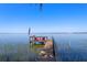 Waterfront property featuring a wooden dock with red Adirondack chairs and an American flag overlooking the serene lake at 11215 Dead River Rd, Tavares, FL 32778
