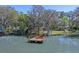 Aerial view of dock featuring two red Adirondack chairs with lake view and a beautiful yard with mature trees at 11215 Dead River Rd, Tavares, FL 32778