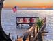 Waterfront dock with two Adirondack chairs faces west for a beautiful sunset over the water at 11215 Dead River Rd, Tavares, FL 32778