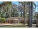Charming brick home featuring mature trees and a well-manicured front lawn and circular driveway at 11215 Dead River Rd, Tavares, FL 32778