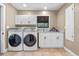 Laundry room with modern washer and dryer, white cabinetry, and tiled floors, blending utility with style at 11215 Dead River Rd, Tavares, FL 32778