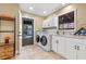 Functional laundry room with modern washer and dryer, white cabinetry, and outdoor access, designed for convenience at 11215 Dead River Rd, Tavares, FL 32778