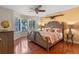 This bedroom features a ceiling fan, hardwood floors, shutters, and a bed at 11215 Dead River Rd, Tavares, FL 32778