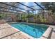 Screened in pool area, featuring a pool with brick surround and lounge seating in lush outdoor space at 11215 Dead River Rd, Tavares, FL 32778