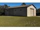 Large detached garage featuring multiple roll-up doors, suitable for vehicle storage or a workshop at 11701 Layton St, Leesburg, FL 34788