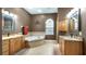 Luxurious bathroom featuring double sinks, a soaking tub, and a large window, creating a spa-like experience at 12127 Cypress Landing Ave, Clermont, FL 34711