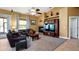 Living room with stone fireplace, entertainment center, carpet, ceiling fan, and a large window at 12127 Cypress Landing Ave, Clermont, FL 34711
