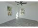 Bright bedroom with hardwood floors, ceiling fan, and two windows providing ample natural light at 1307 E Harding St, Orlando, FL 32806