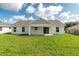 Expansive backyard with lush green lawn and white exterior of the home with covered patio at 13334 Sw 107 St, Dunnellon, FL 34432