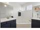 Bathroom featuring double sinks, a soaking tub, decorative windows, and updated fixtures at 13753 Via Roma Cir, Clermont, FL 34711