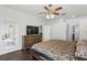 Bedroom featuring a ceiling fan, TV on dresser, and a doorway to a bathroom with dark wood flooring at 13753 Via Roma Cir, Clermont, FL 34711