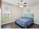 Bedroom features a ceiling fan, large window, and dark wood flooring throughout the space at 13753 Via Roma Cir, Clermont, FL 34711