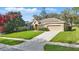 Well-maintained single-Gathering home featuring lush green lawn and a long driveway on a sunny day at 13753 Via Roma Cir, Clermont, FL 34711