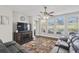Spacious living room with dark wood floors, a ceiling fan, and large windows overlooking the pool area at 13753 Via Roma Cir, Clermont, FL 34711