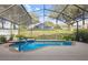 Relaxing screened-in pool featuring a waterfall, blue handrail, and a serene backyard view at 13753 Via Roma Cir, Clermont, FL 34711
