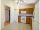 A bright kitchen featuring wooden cabinets, white appliances, and tile flooring at 13828 Se 85Th Cir, Summerfield, FL 34491