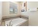 A bathtub is tiled with a decorative stripe and a large window that provides an exterior view at 1524 Flange Dr, Davenport, FL 33896
