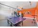 Versatile garage space with vibrant orange accents, featuring a ping pong table and recreational setup at 1524 Flange Dr, Davenport, FL 33896