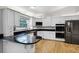 Modern kitchen with white cabinets, granite countertops, stainless steel appliances, and hardwood floors at 16017 Harbar Oaks Dr, Montverde, FL 34756