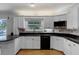 Modern kitchen features white cabinets, black countertops, and stainless steel appliances at 16017 Harbar Oaks Dr, Montverde, FL 34756