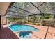 Screened-in pool and hot tub surrounded by brick patio with lush landscaping and seating area at 16017 Harbar Oaks Dr, Montverde, FL 34756