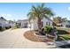 Attractive single-story home with a circular driveway, white exterior, and verdant landscaping featuring a tall palm tree at 16800 Se 80Th Bathurst Ct, The Villages, FL 32162