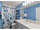 Blue bathroom with a floral shower curtain, white vanity, and shelves at 17291 Saw Palmetto Ave, Clermont, FL 34714