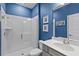 Modern bathroom featuring a glass-enclosed shower and vanity with blue walls at 17291 Saw Palmetto Ave, Clermont, FL 34714