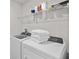 Neat laundry room with new white washer and dryer and ample shelving for storage at 17291 Saw Palmetto Ave, Clermont, FL 34714