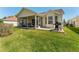 Well-maintained backyard with a screened lanai, a patio featuring a barbeque grill, and a lush lawn at 17416 Se 71St Currituck Ter, The Villages, FL 32162