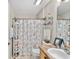 Cozy bathroom featuring a charming beach-themed shower curtain and ample shelving for storage at 17416 Se 71St Currituck Ter, The Villages, FL 32162