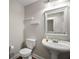 Stylish powder room with pedestal sink, decorative mirror, floating shelves, and wood-look floors at 17421 Woodfair Dr, Clermont, FL 34711